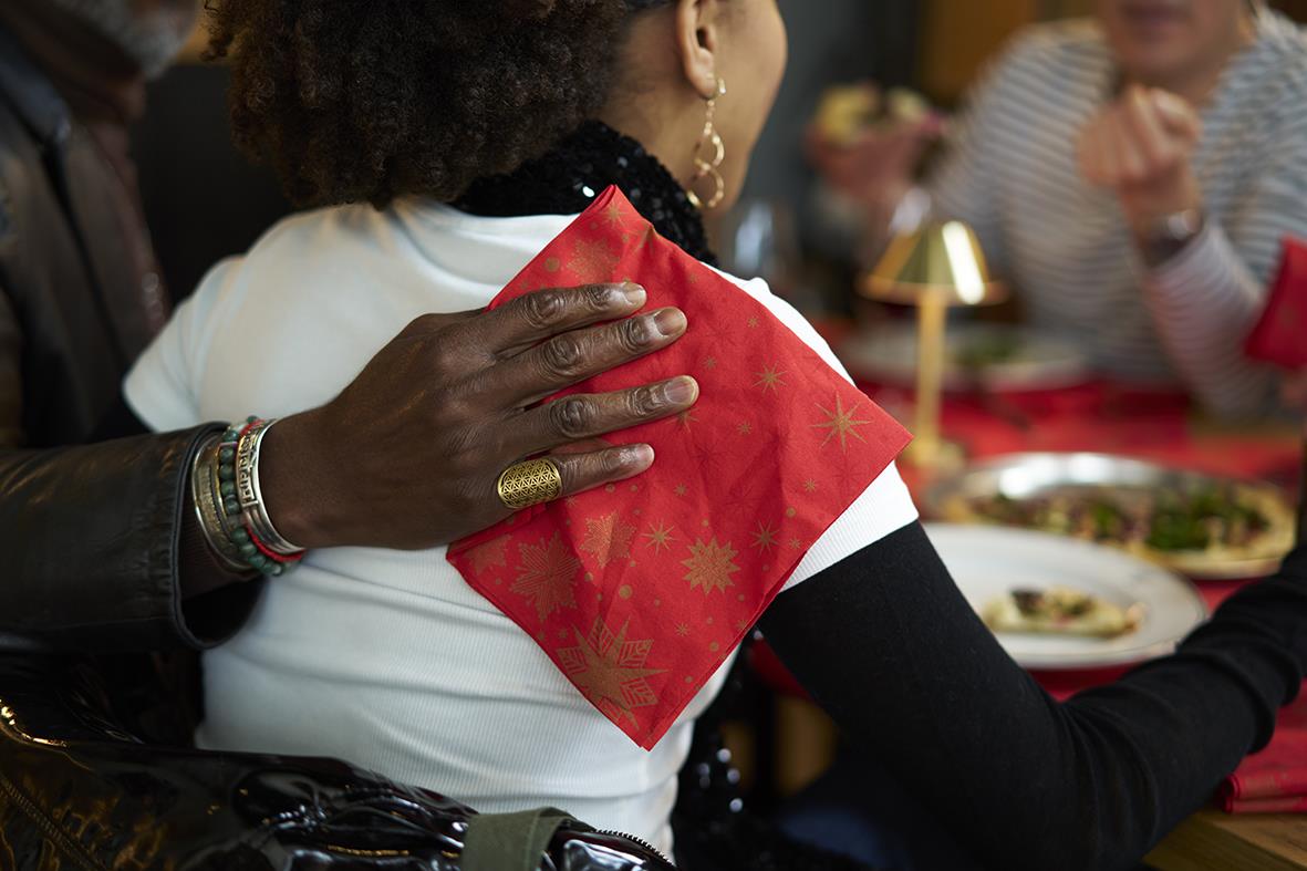 Person som bär en röd julduk på axeln under en festlig middag