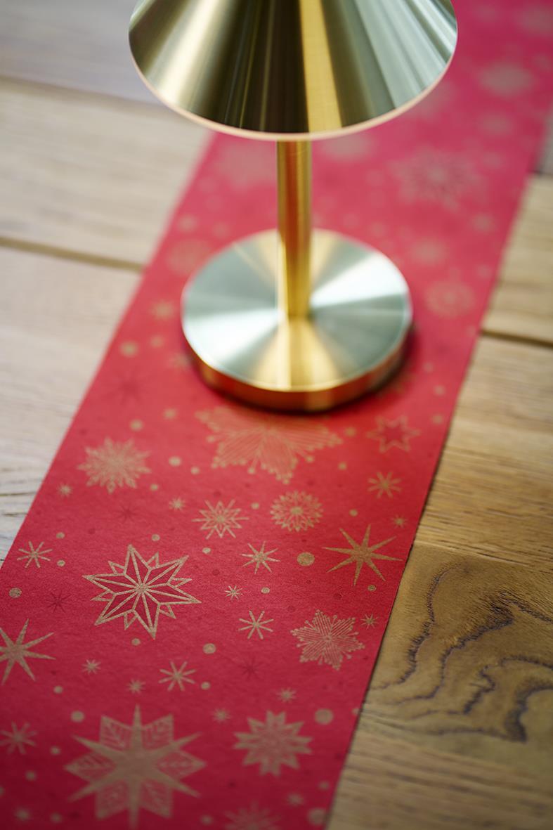 Röd löpare med guldiga snöflingor och stjärnor under ett guld- och silverfärgat ljusstake