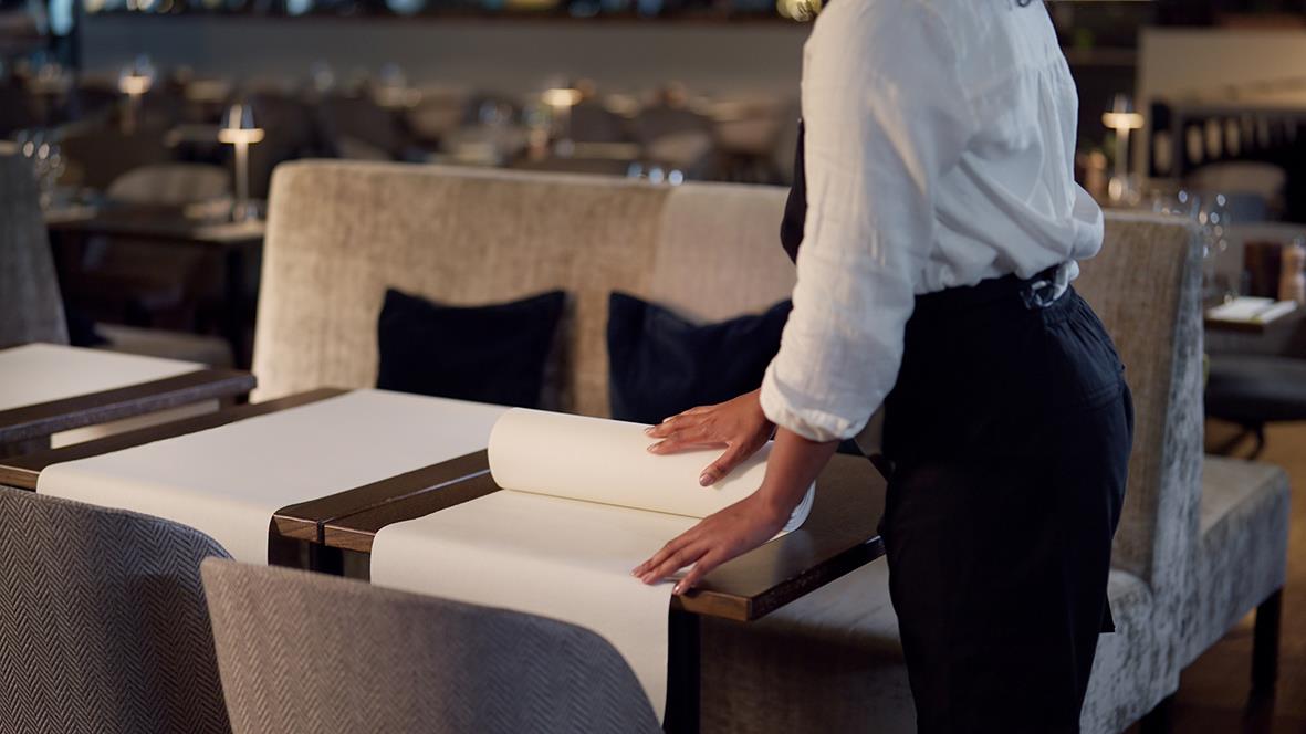Person placerar en vit vepa på ett bord i ett restaurang- eller caféutrymme