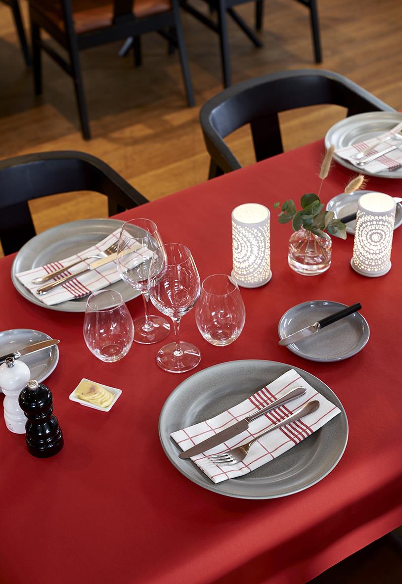 Röd servett på dukat bord med glas, tallrikar och ljuslyktor i ett matsalsmiljö