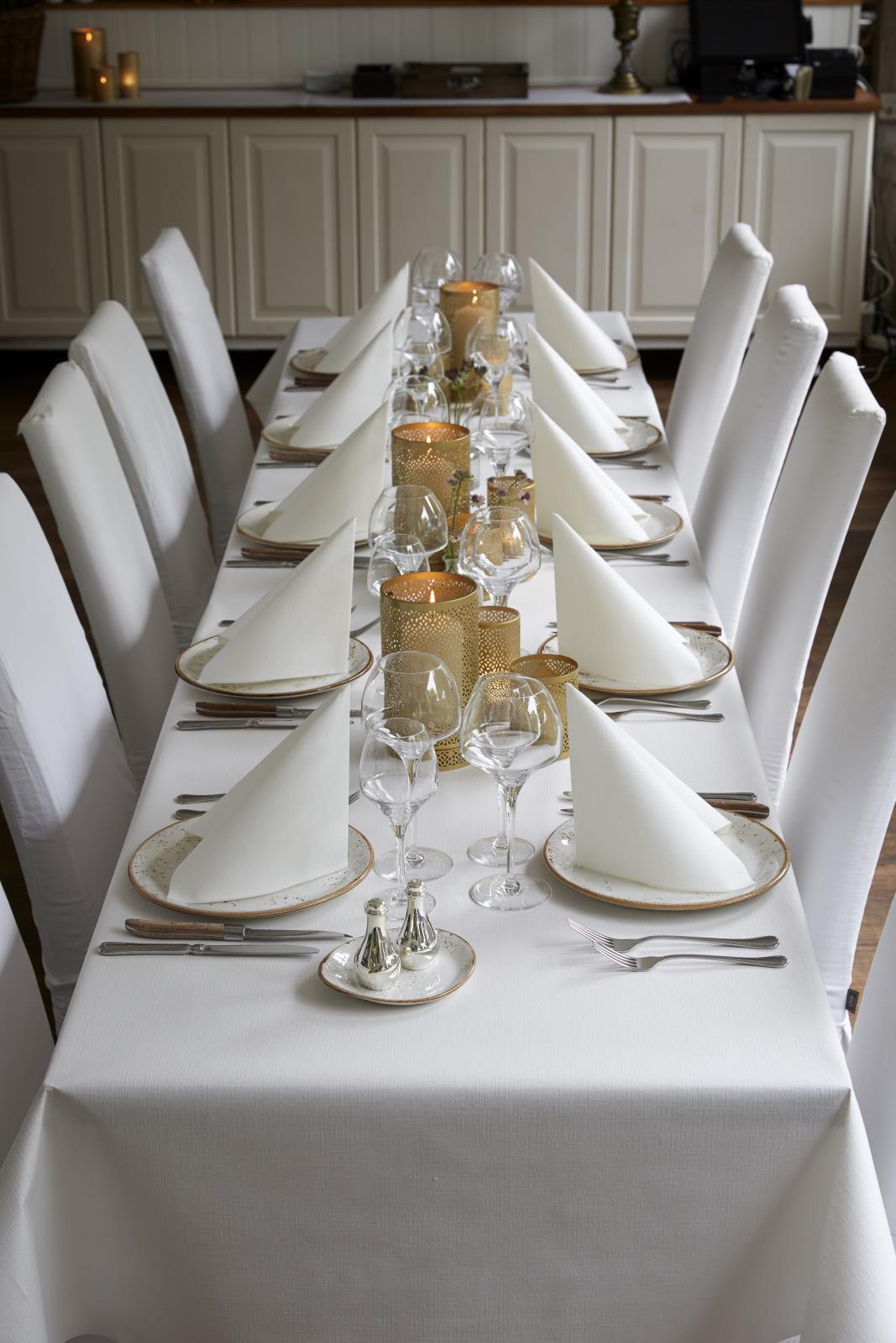 Vitt dukat med servetter, glas och ljuslyktor på ett bord för middagsbjudning