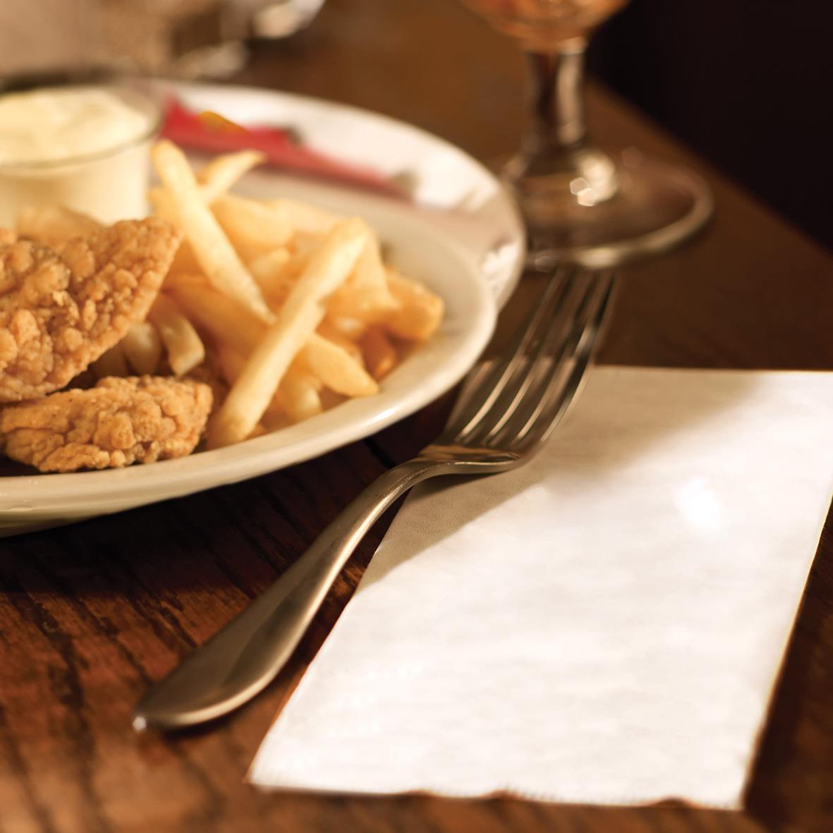 Vit servett på bordet bredvid en tallrik med mat och bestick