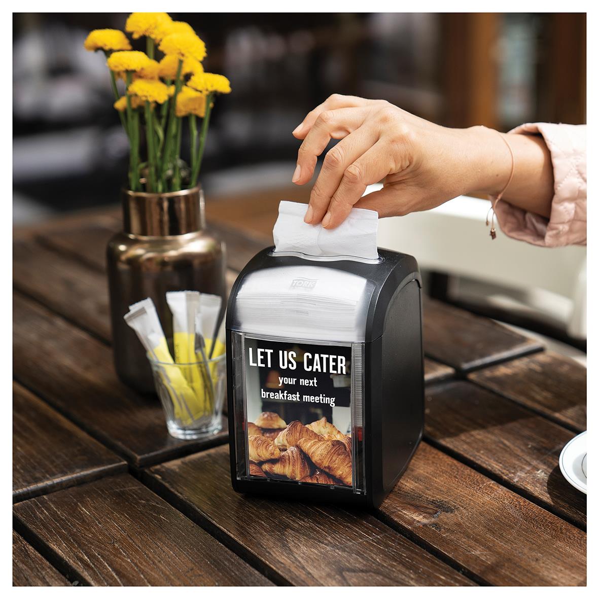 Dispenserservett Tork N14 2-lag vit 16,5x21,3cm i svart dispenser på träbord med blommor