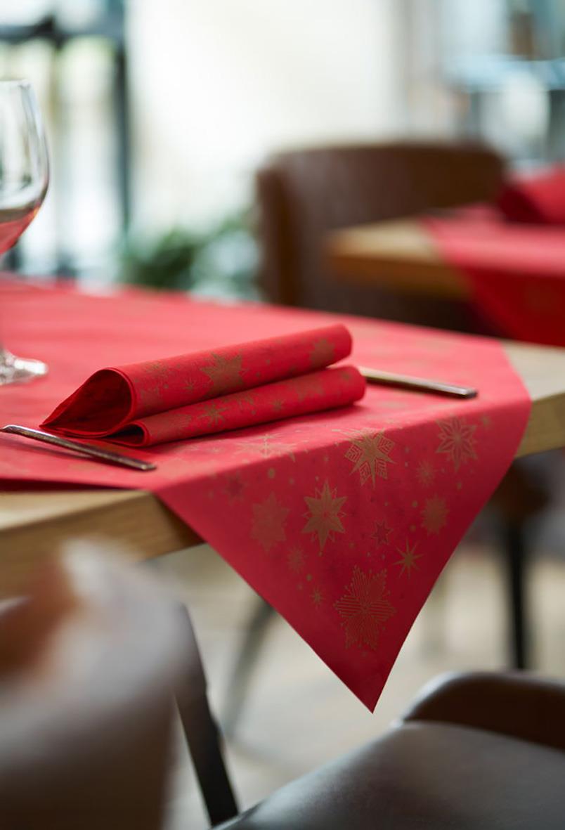 Röd servett med guldstjärnor på dukning med bestick och glas i ett restaurangmiljö