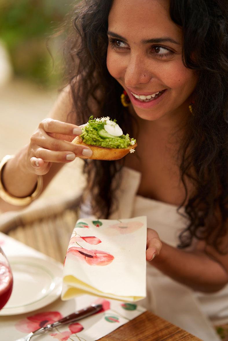 Kvinna som äter en smörgås med guacamole och ägg, med en servett Duni Dunisoft Poppy Charm 40x40cm i bakgrunden