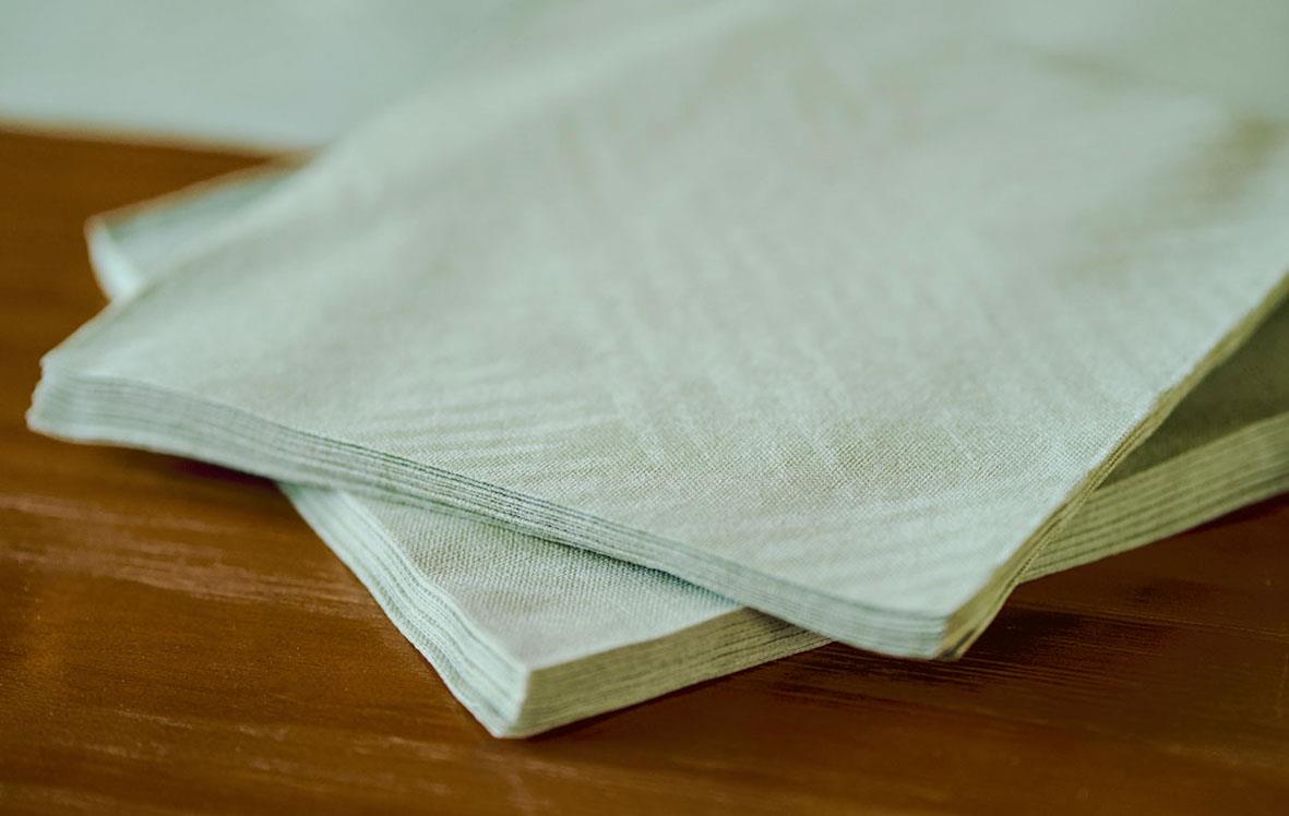 Vit servett av Duni Dunisoft Loom 40x40cm staplad på träbord
