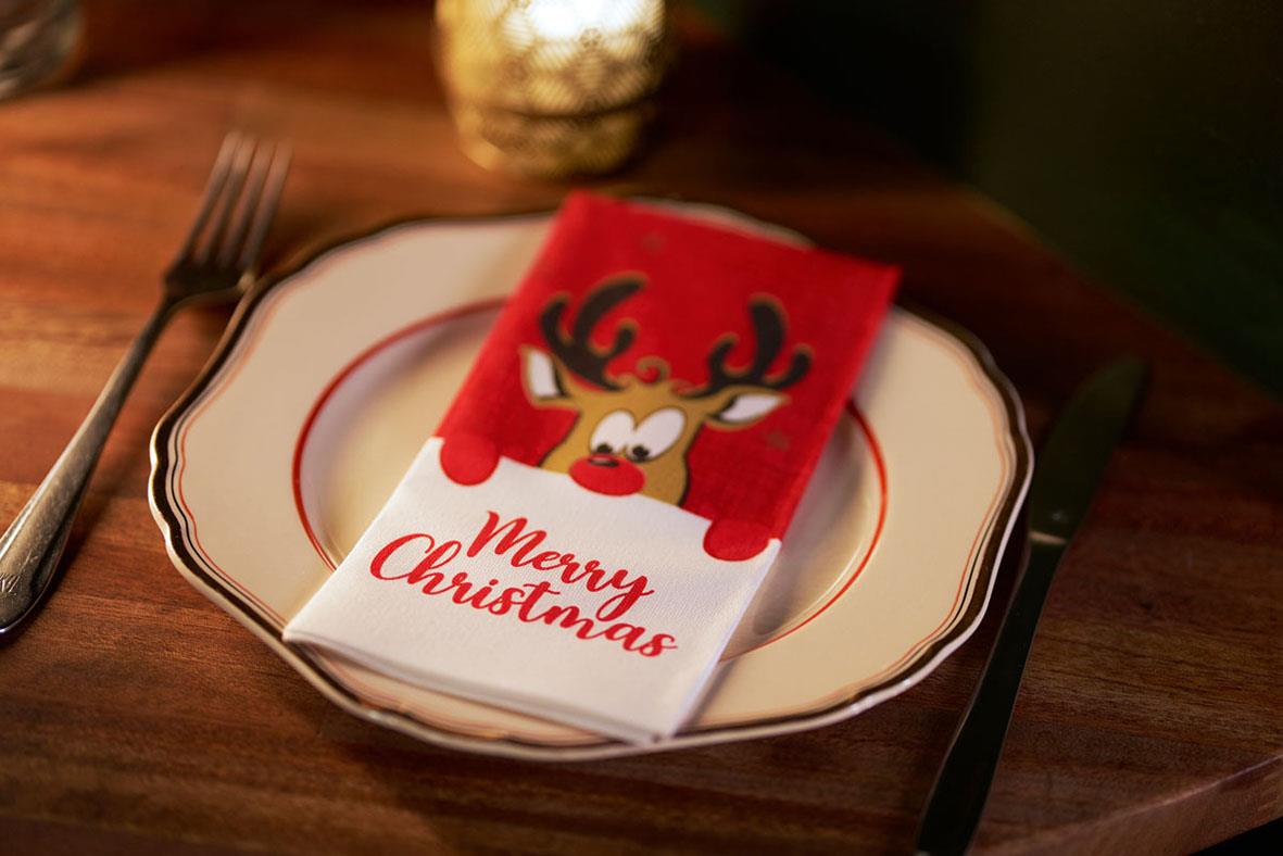Julservett med renhornsdesign och text Merry Christmas på ett fat med bestick