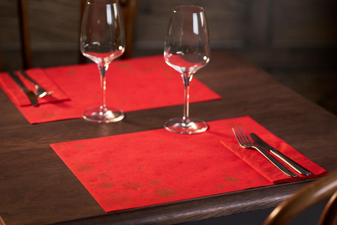Två tomma vinglas och bestick på röda servetter på ett bord