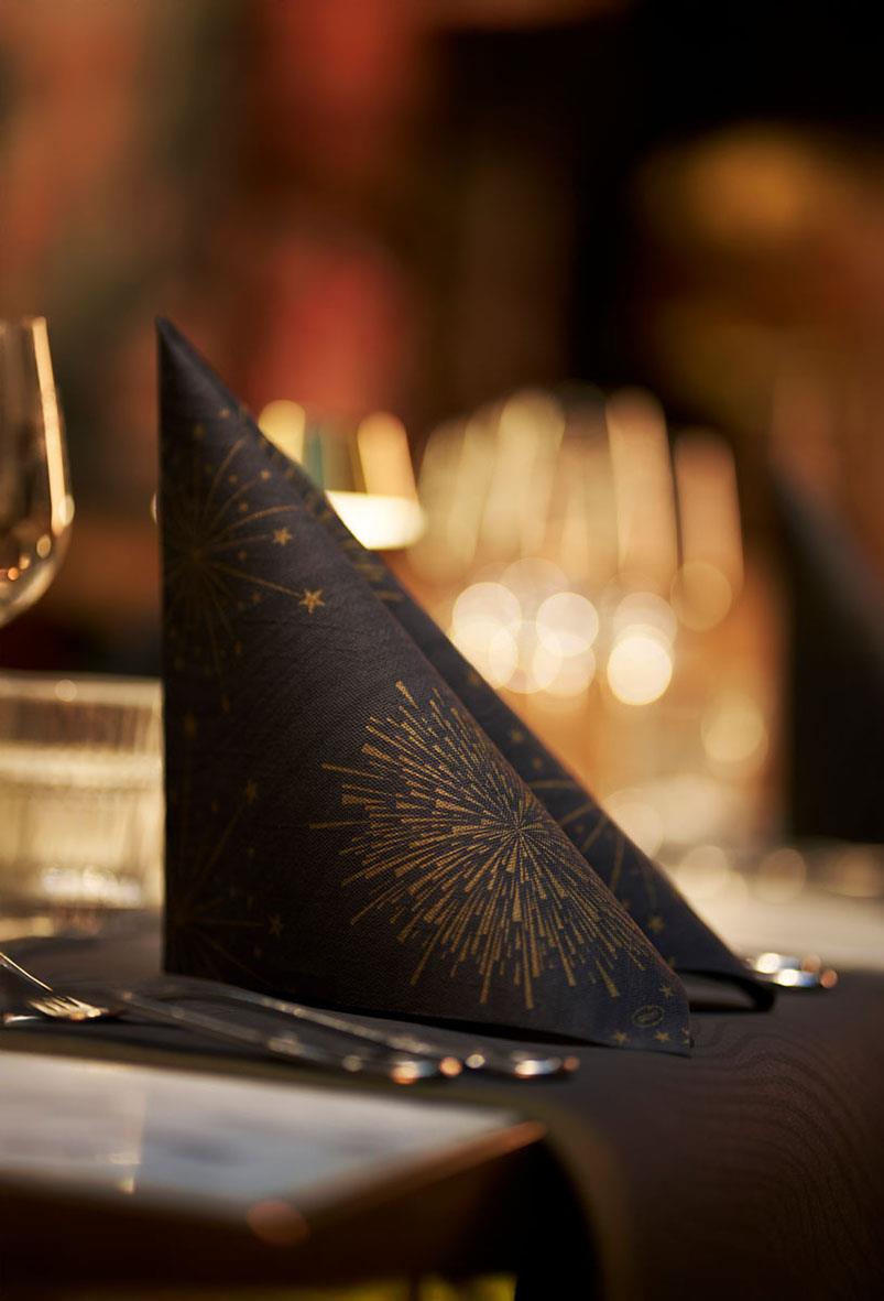 Svart servett med guldstjärnor och fyrverkerimönster på ett festbord
