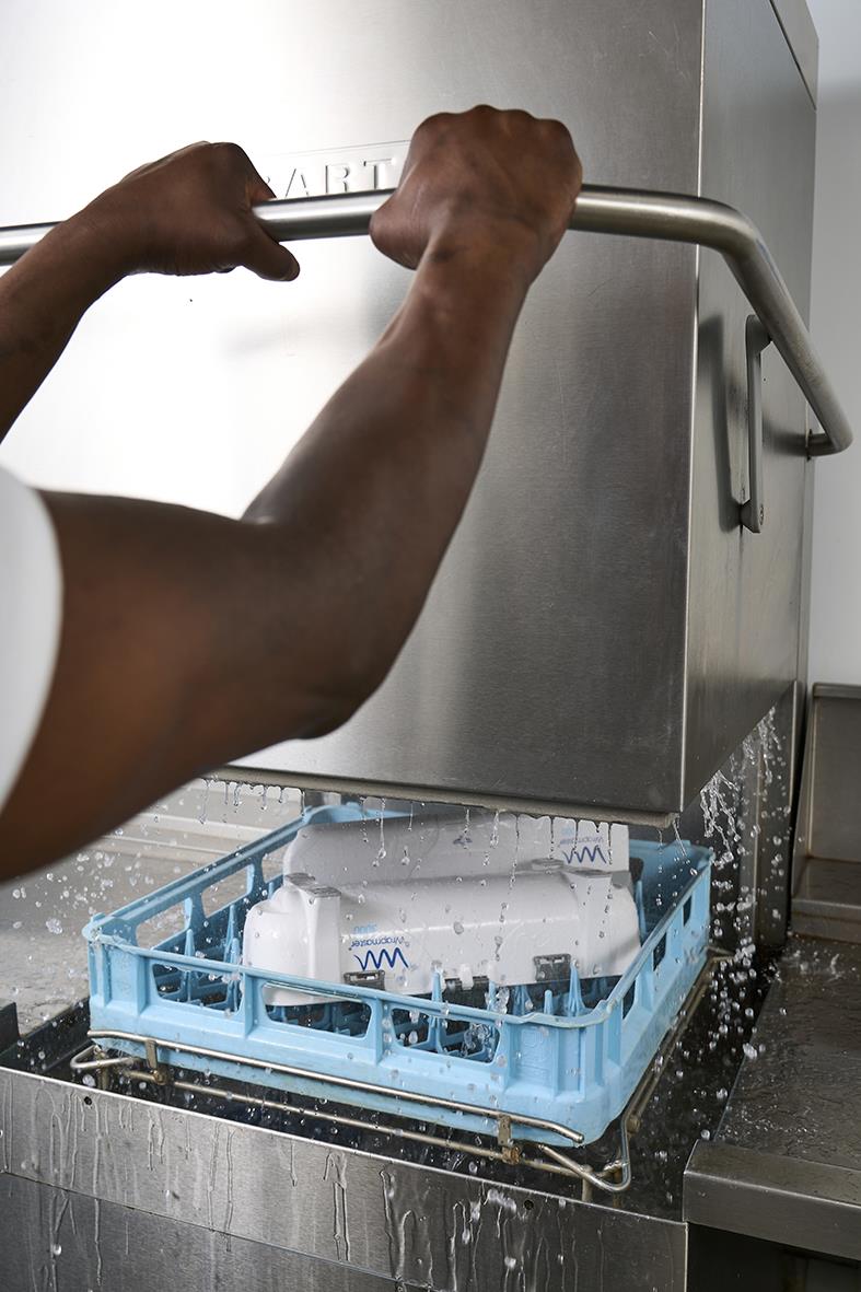 Person som använder Dispenser Wrapmaster 3000 för att rulla plastfilm i ett kök eller matlagningsmiljö