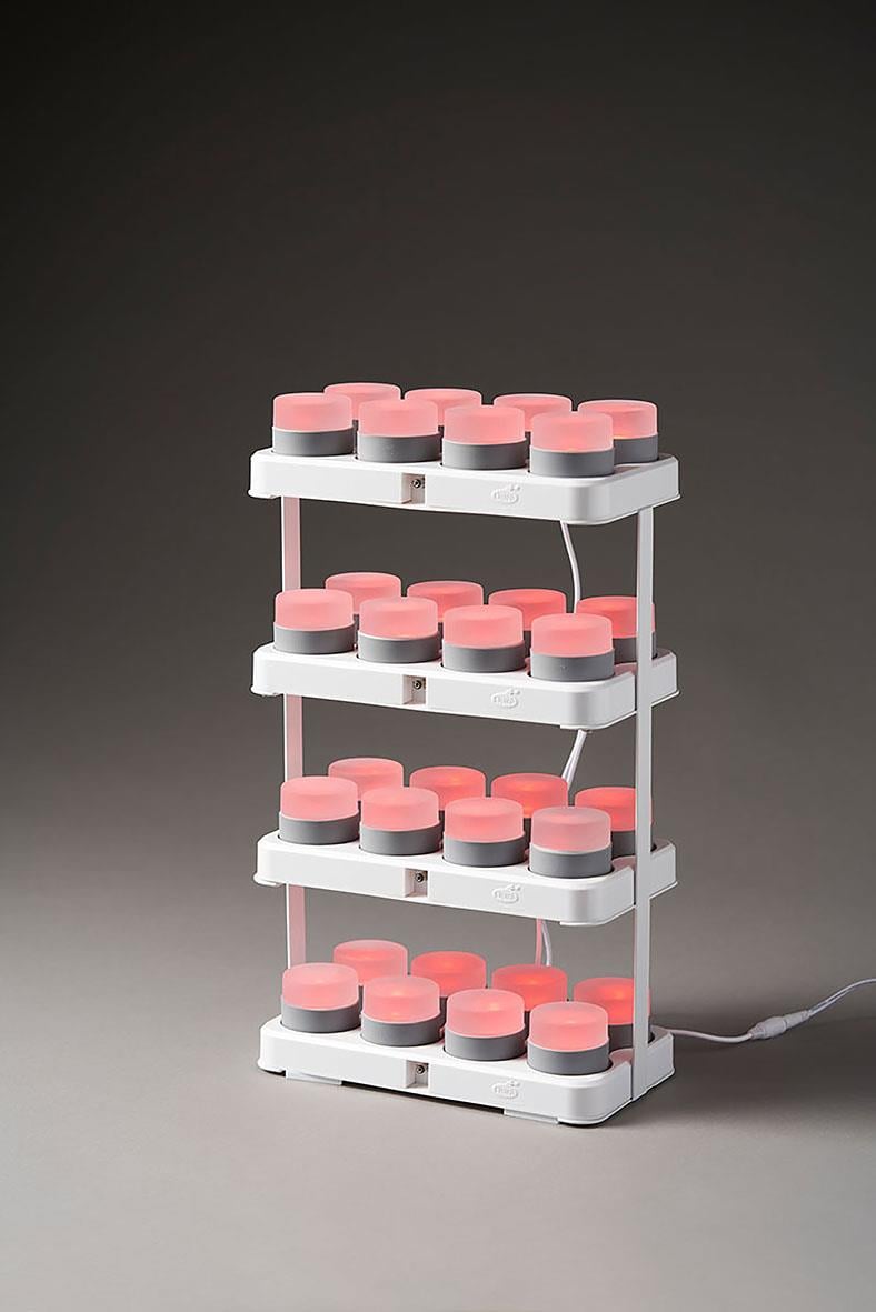 Vit laddningsstation med flera små behållare med rosa lock, fyra hyllplan och sladd