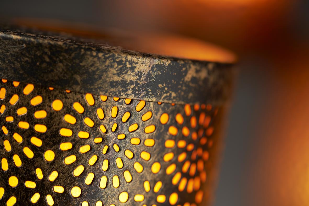 Närbild av metall ljushållare med LED-ljus som lyser igenom perforerad design