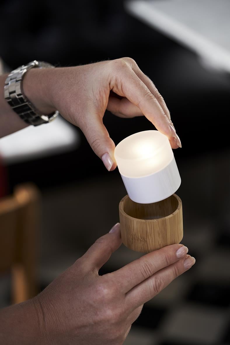 Person som placerar LED-ljushållare i bambufot med ljus inuti