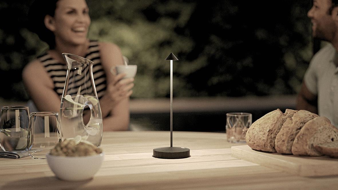 Bordslampa LED Securit Angelina svart på ett bord med bröd och drycker, utomhusmiljö