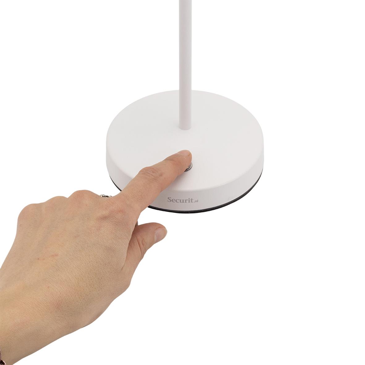Hand trycker på knapp på vit bordslampa LED Securit Angelina