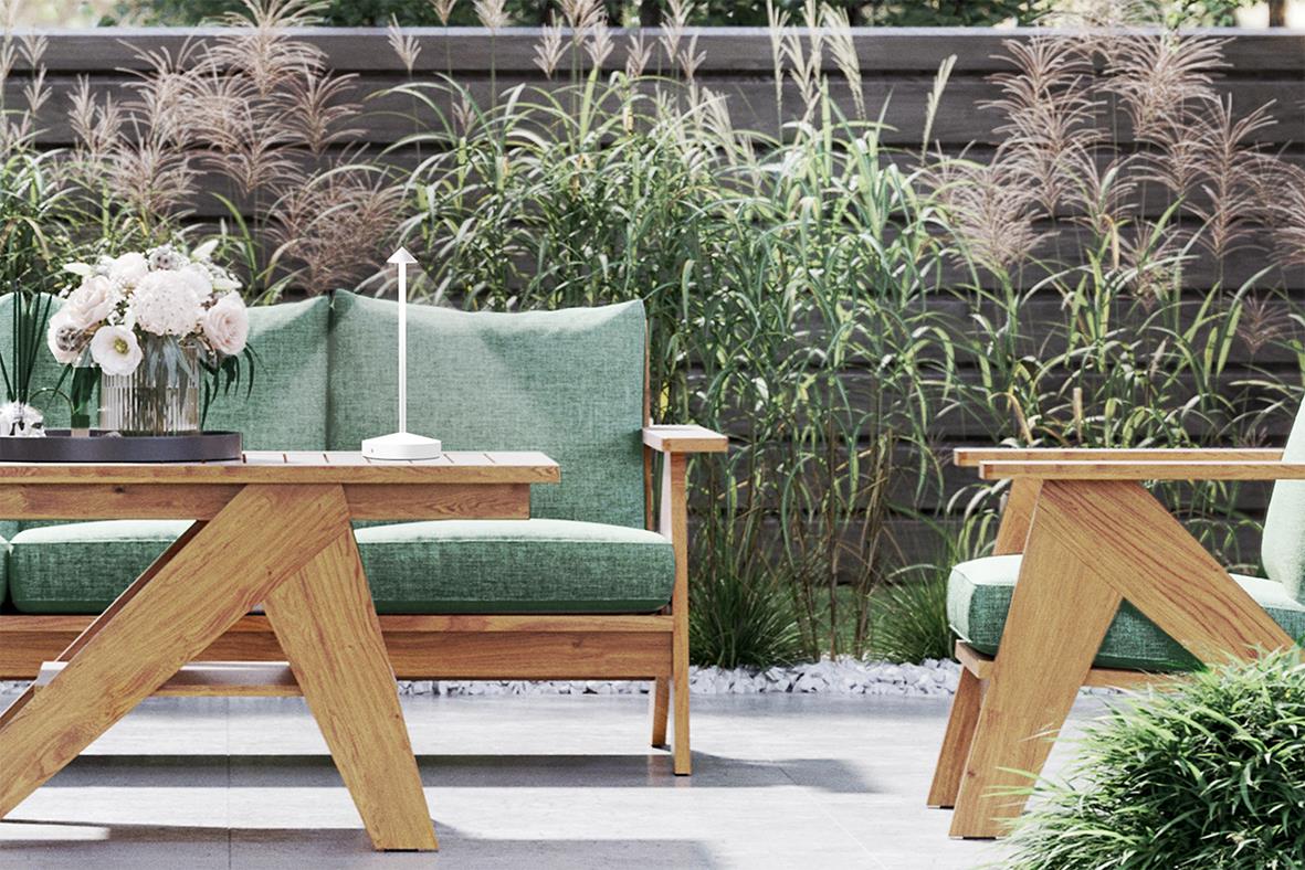 Utomhusplats med träbord, gröna soffor och växter i bakgrunden