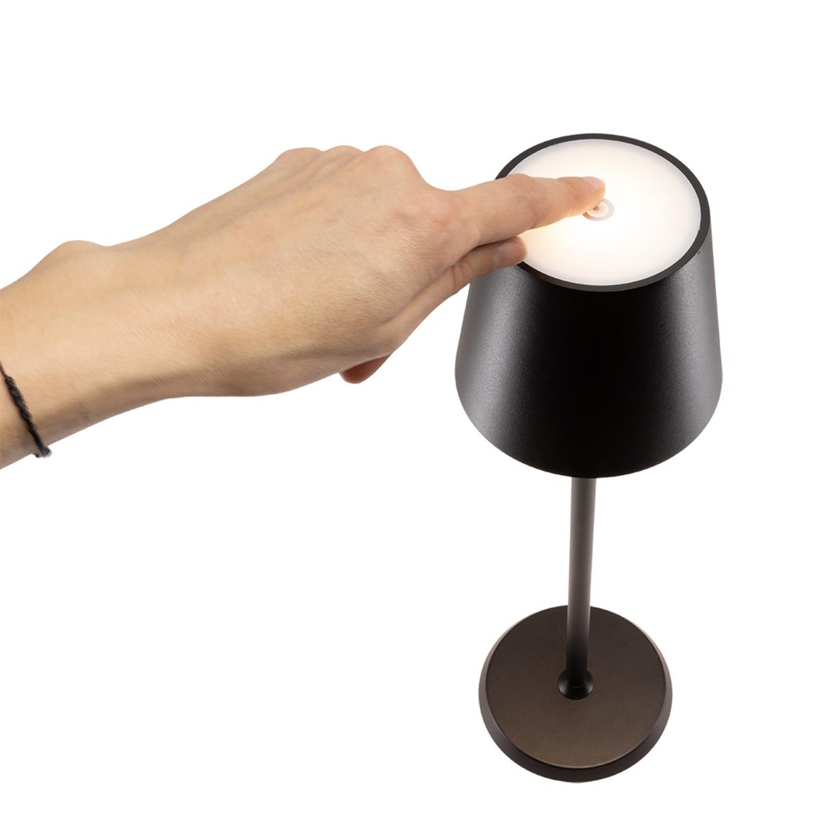 Hand som trycker på LED-lampa i svart bordslampa Feline