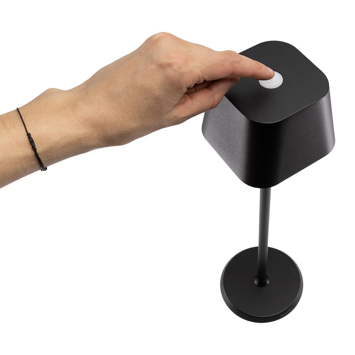 Hand som trycker på en knapp på en svart bordslampa LED Securit Georgina Svart