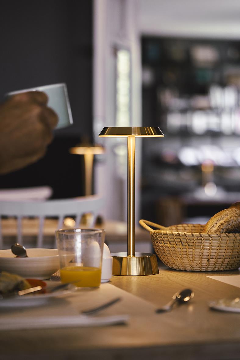 Bordslampa LED Duni Nour i mässing på ett matbord med frukost och bestick