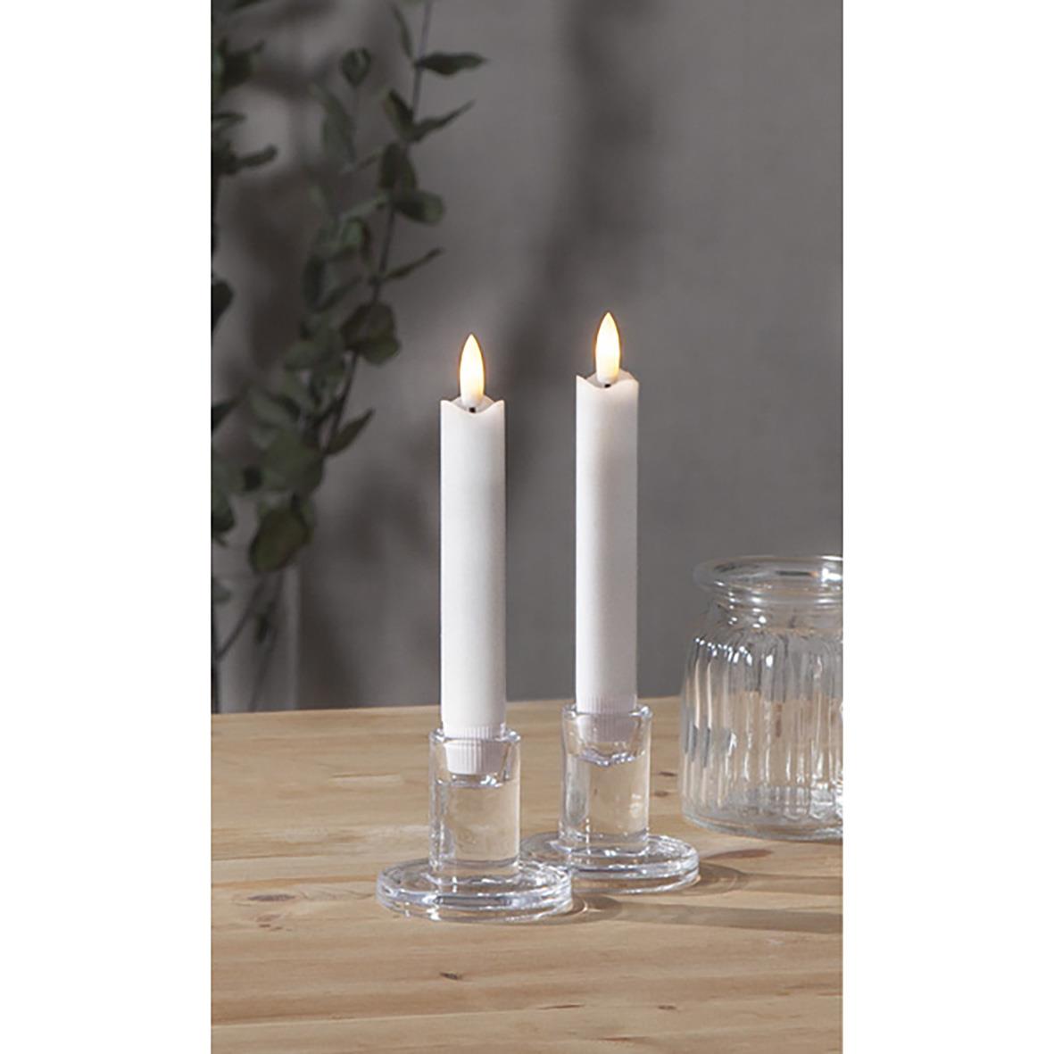 Antikljus LED Flamme i glas, tända med varm glöd, placerade på ett träbord med ett glas till höger