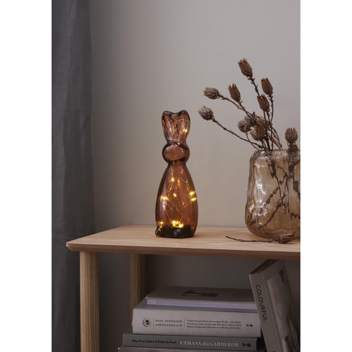 Glasdekoration Harry Brun i form av en katt på ett bord med en vas och böcker