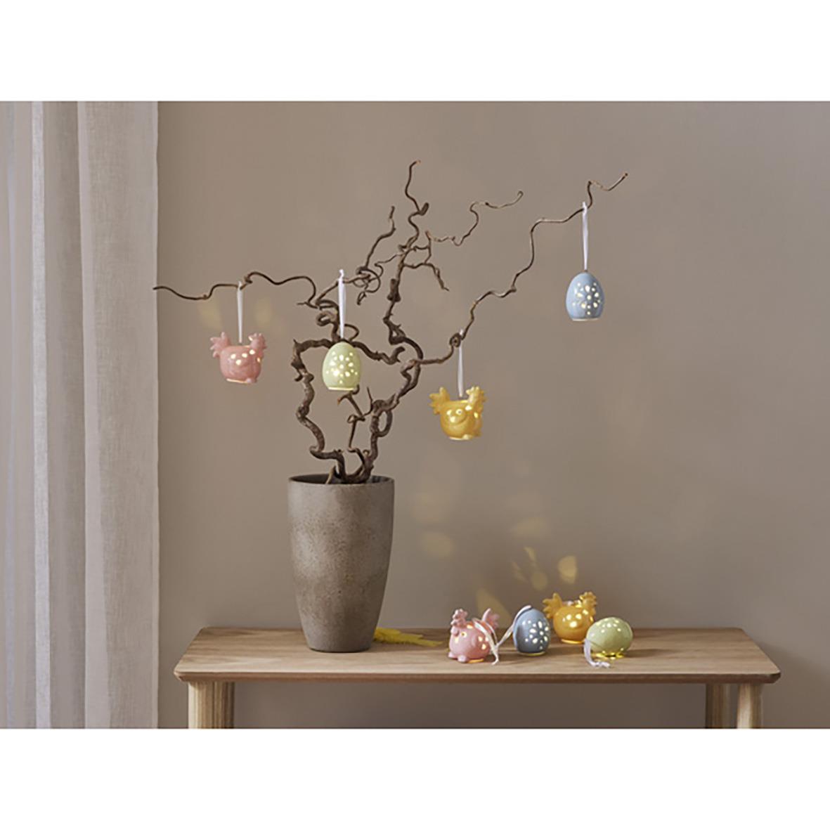 Dekorationsfigurer Esther i form av små kaniner i pastellfärger hängande från en gren i en vas