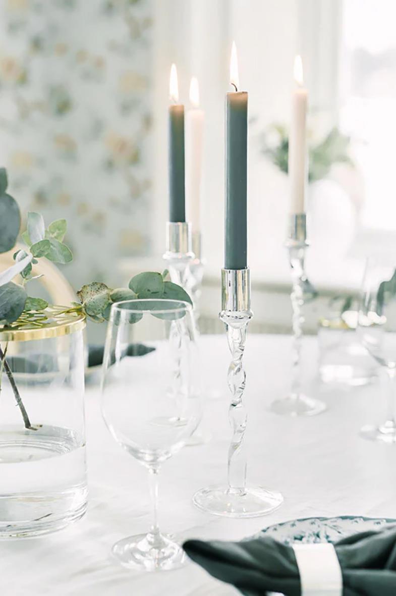 Ljusstake Dorre Glas med silvertopp 27cm med tre tända ljus på ett bord med glas och dekorationer