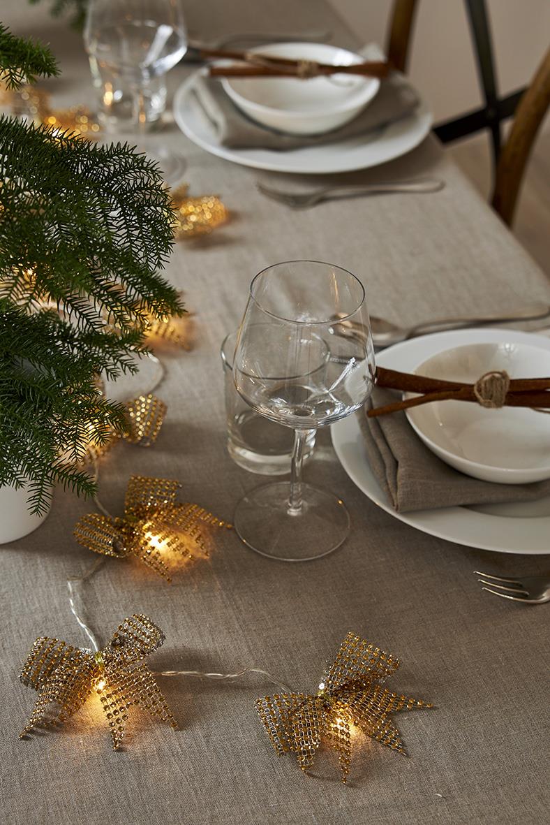 Gul ljusslinga i form av stjärnor på ett julbord med glas, tallrikar och bestick