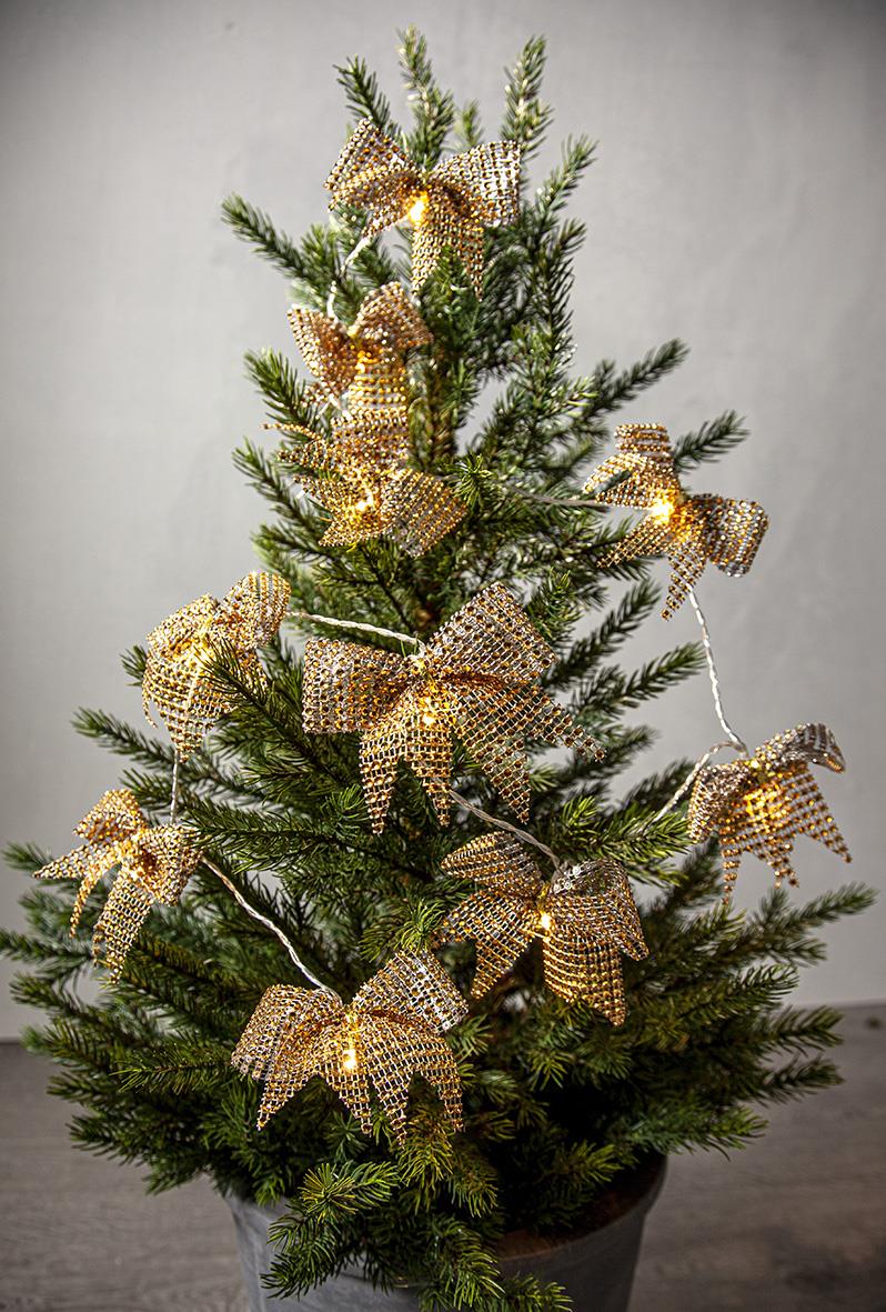 Liten julgran med ljusslinga och stora guldglittriga rosetter