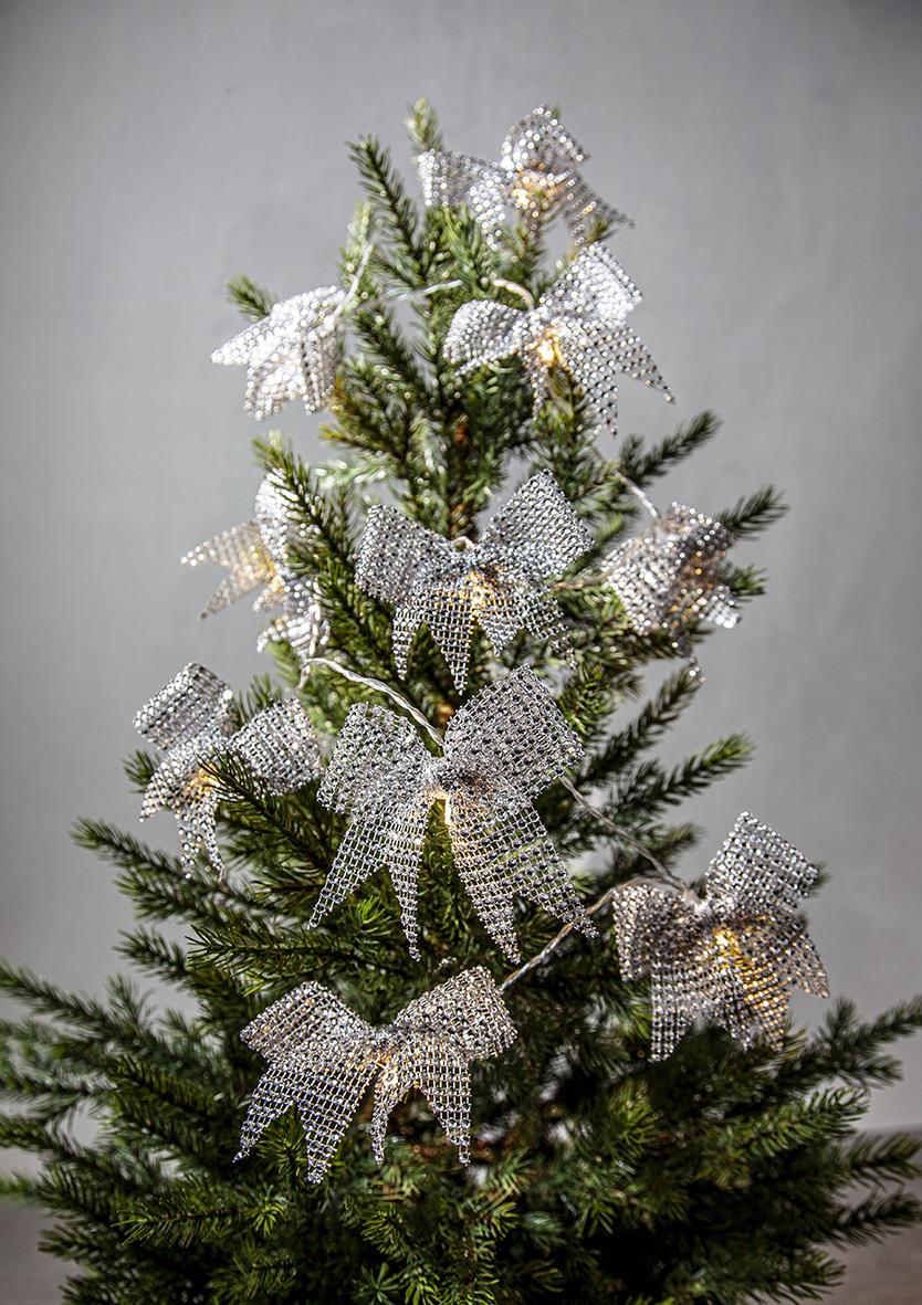 Julgran med silverglittriga rosetter och ljusslinga