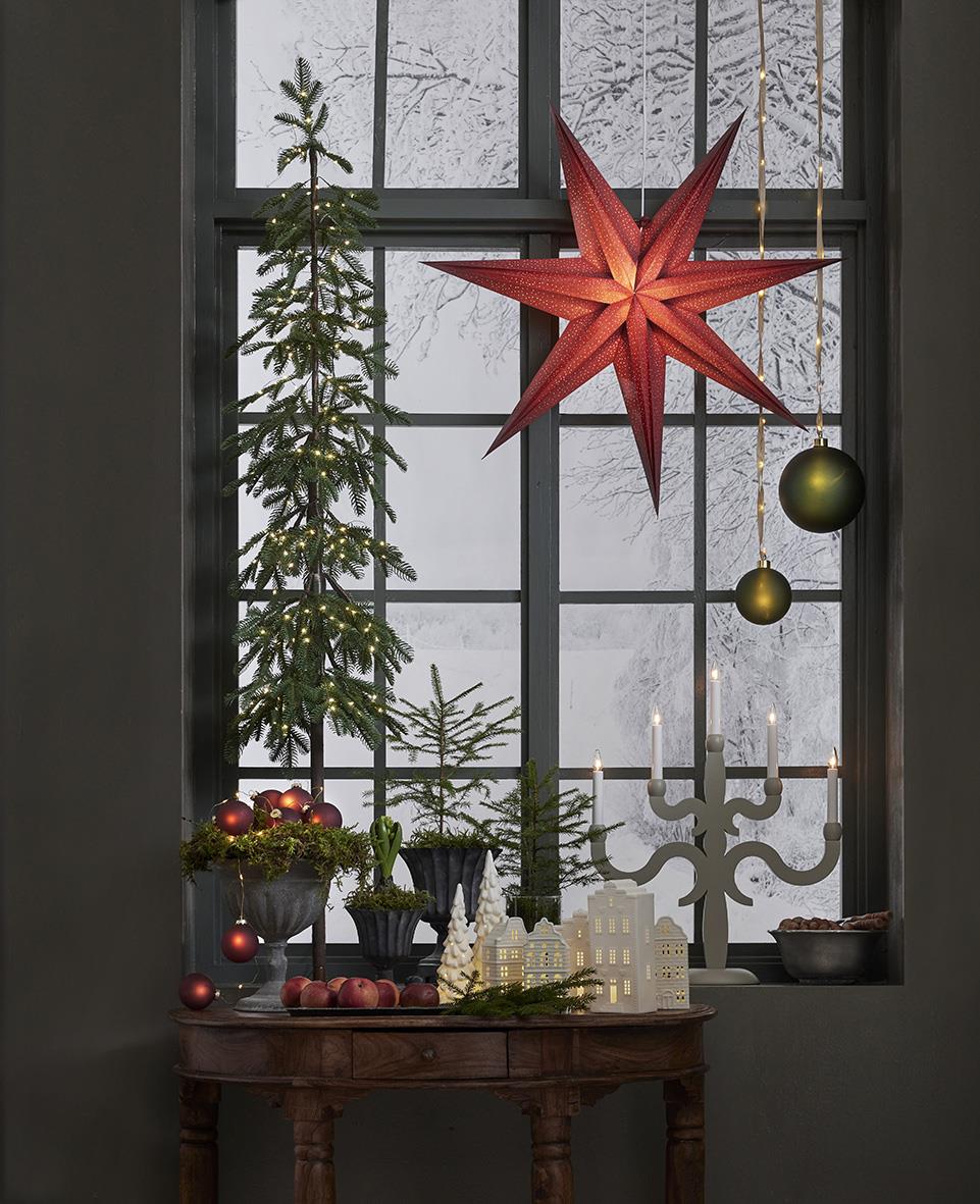 Vinterdekoration med julgran, stjärna och julkulor framför ett fönster