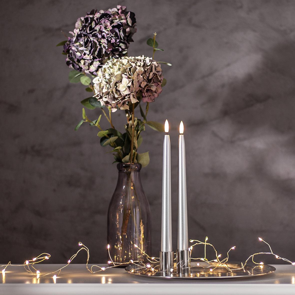 Antikljus Star Trading LED Flamme i metall silver med 28,5 cm höjd, placerad bredvid blommor och ljusslinga