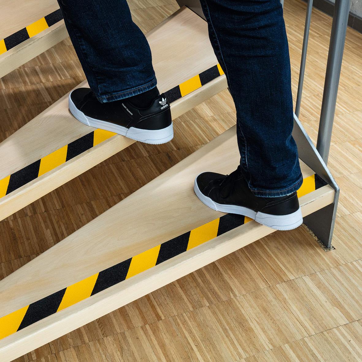 Person står på halkskyddstejpad trappa i gul/svart färg för extra grepp
