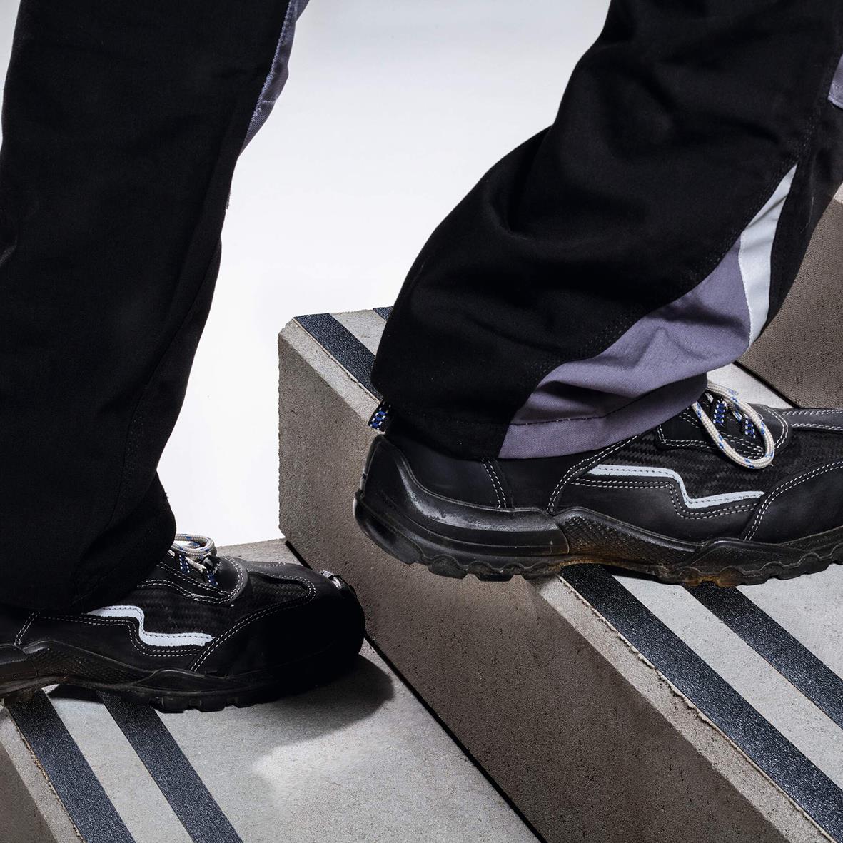 Person står på halkskyddstejp Duraline Grip+ svart under sina skor för att förhindra halka