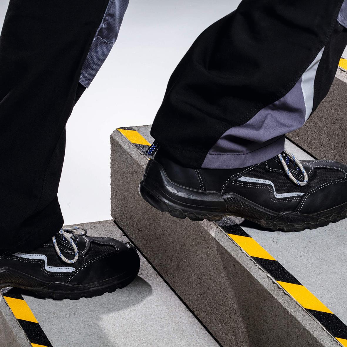 Person står på halkskyddstejp Duraline Grip+ i gul/svart på en tröskel