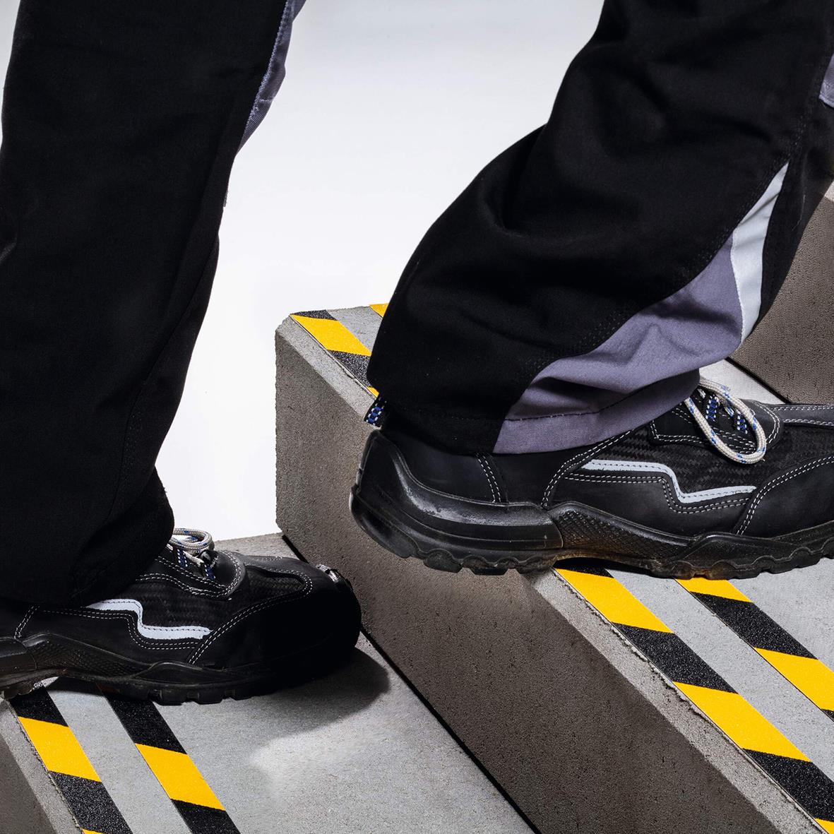 Person står på halkskyddstejp med gul/svart färg och 25mm bredd, använd för att förhindra halka.