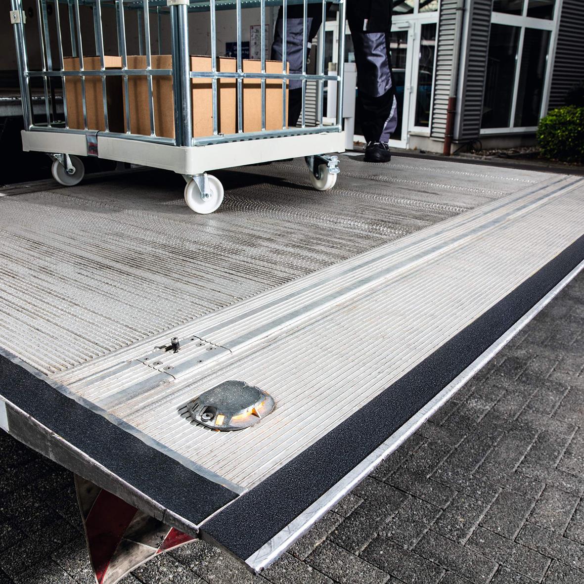 Halkskyddstejp på ramp med lastbil och person i bakgrunden