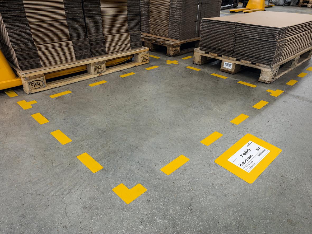 Golvdekal med guldfärgade markeringar och etikett på betonggolv i lager