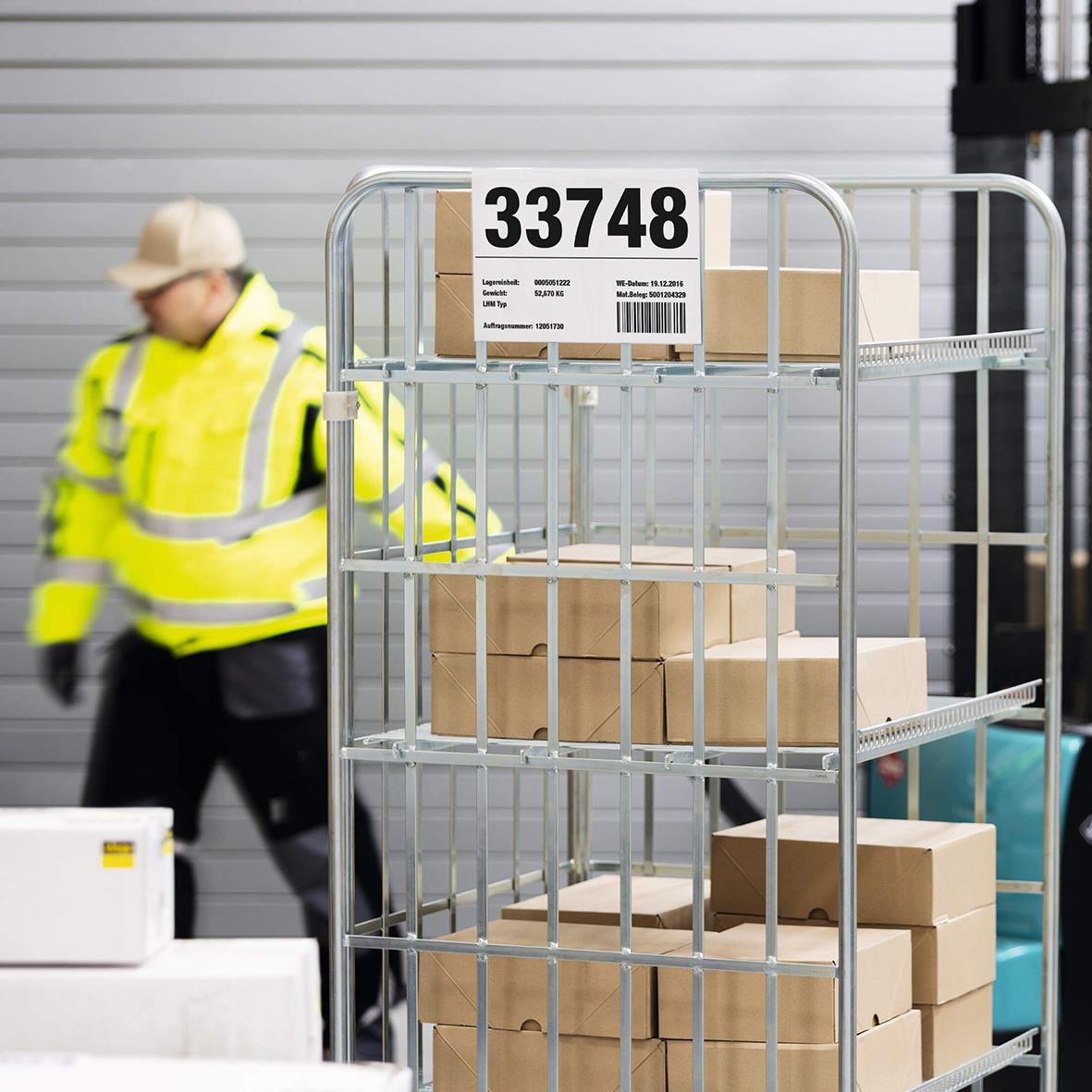 Pallficka hård omslag A4L på vagn med förpackningar och en person i högsynklednad i bakgrunden