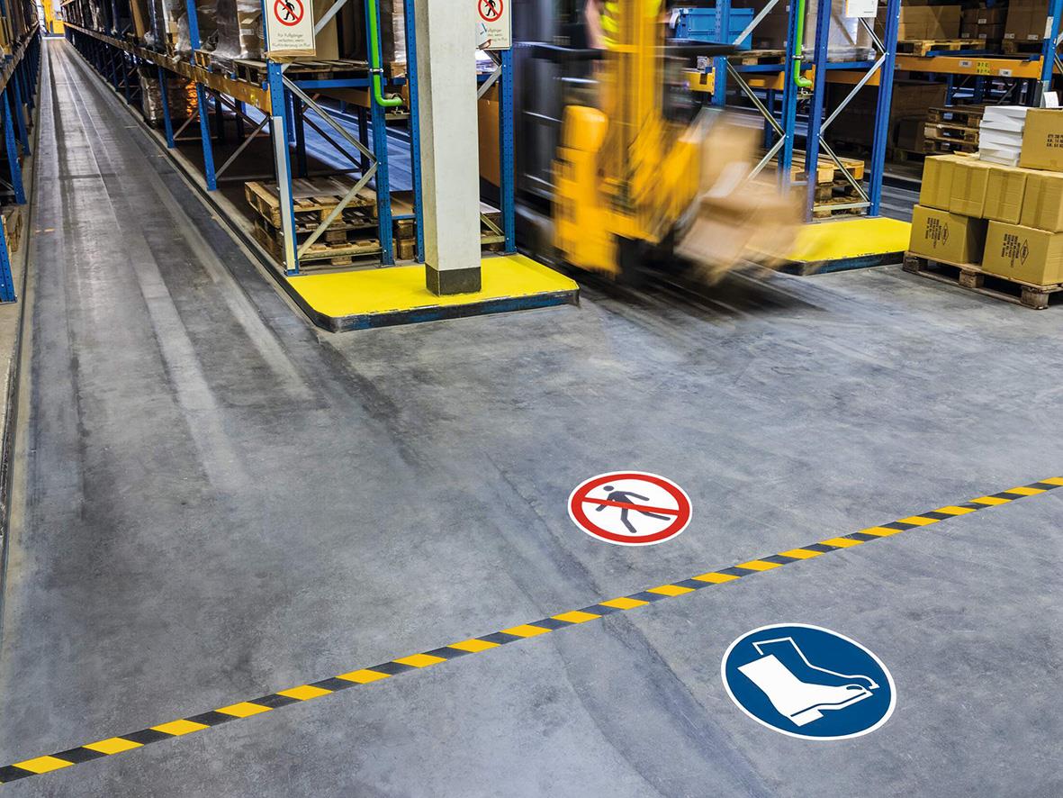 Industriell lagermiljö med varningsmarkeringar och skyddsskor på golvet