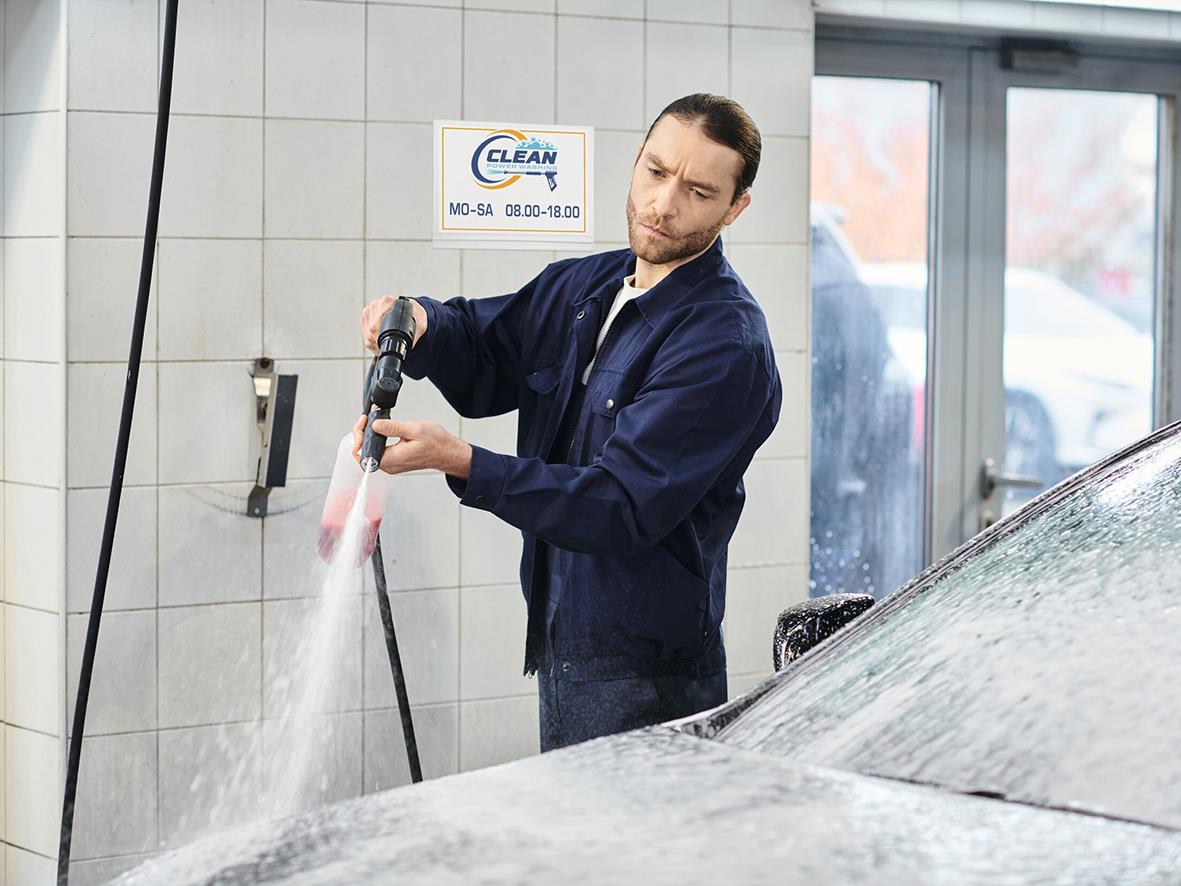 Man tvättar en bil med högtryckstvätt i en garage eller tvätthall