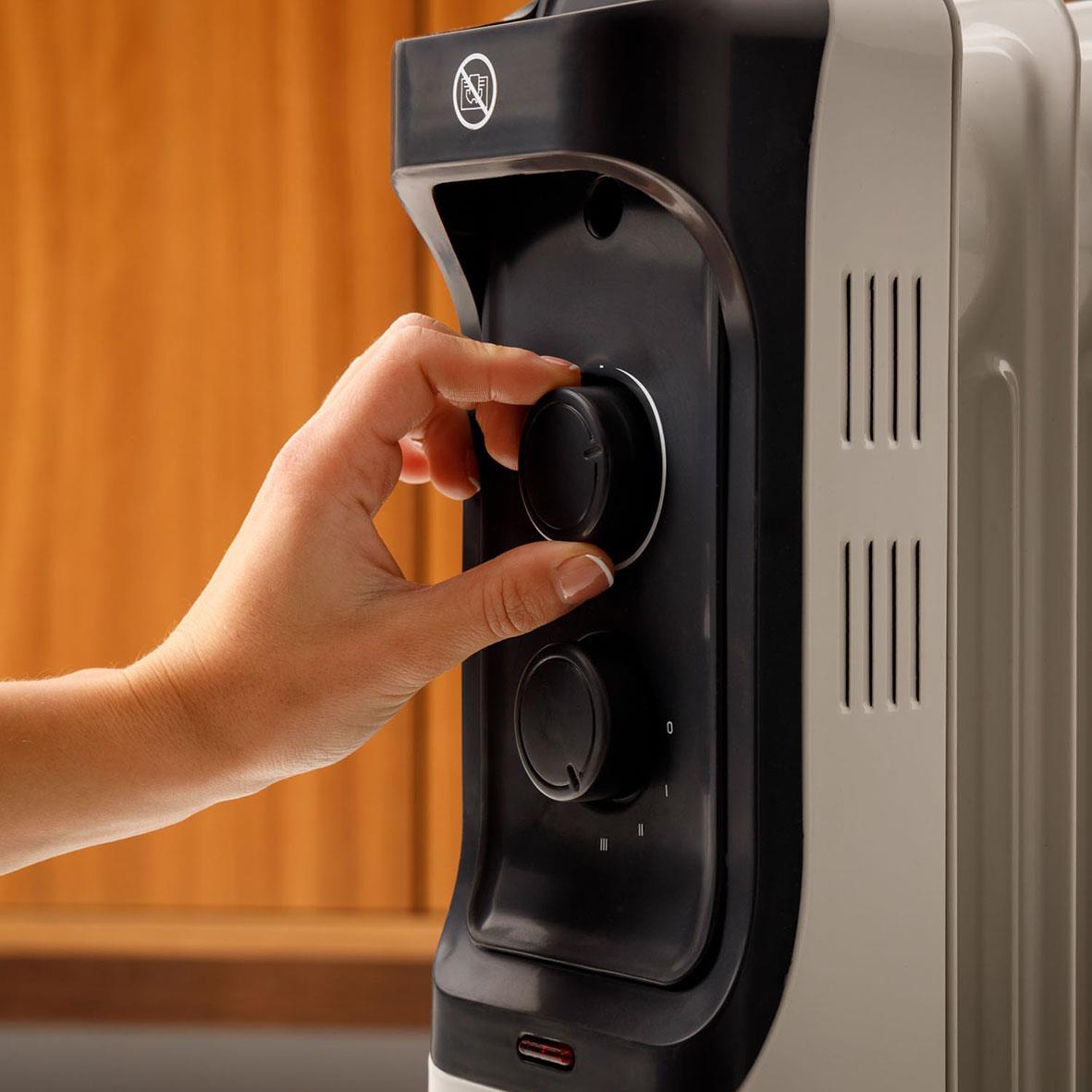 Person som justerar en oljeradiator från Element Targus Oljeradiator New Dakar 1500