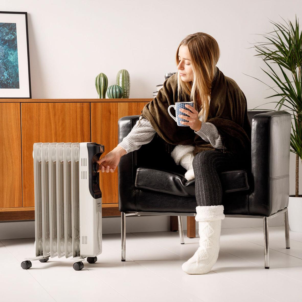 Kvinna justerar Element Targus Oljeradiator New Dakar 1500 i ett vardagsrum