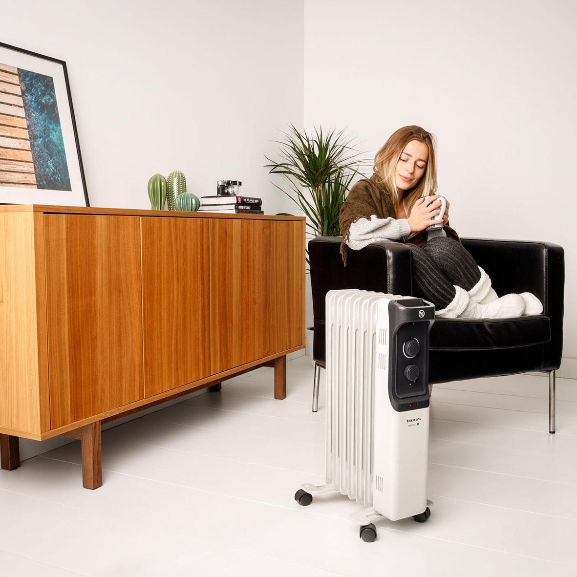 Kvinna sitter på soffa med oljeradiator i ett modernt vardagsrum