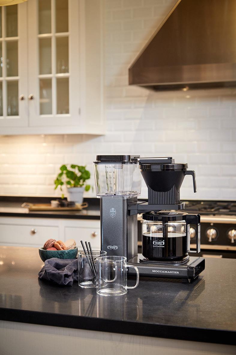 Kaffebryggare Moccamaster Automatic Antracit på köksbänk med glas, kopp och bakgrund av kök