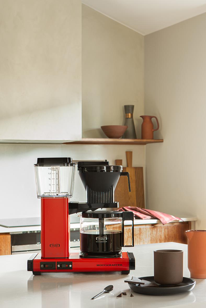 Röd Moccamaster automatisk kaffebryggare på köksbänk med kopp och sked
