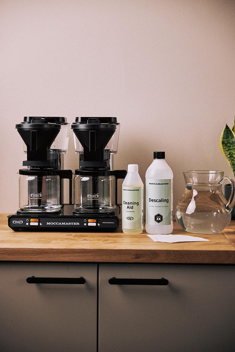 Kaffebryggare Moccamaster Professional dubbel svart och silver med rengöringsmedel och vatten på köksbänk