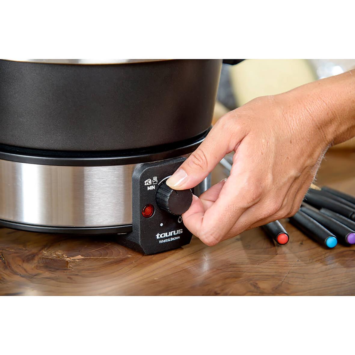 Hand som justerar värmen på en Taurus fonduegryta 1000W