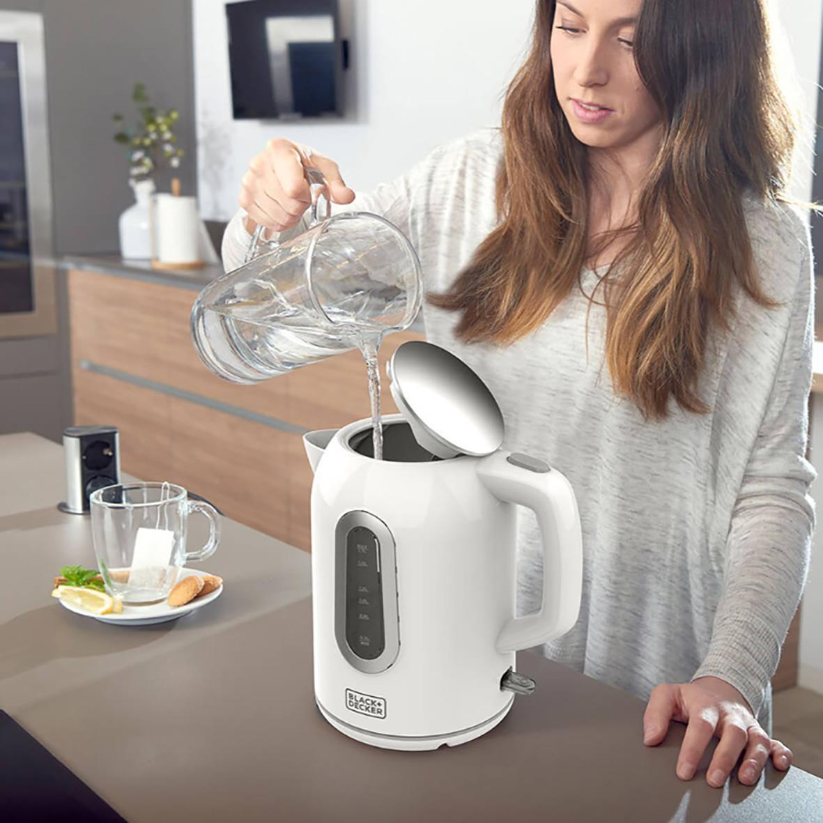 Kvinna häller vatten i en vit vattenkokare Black+Decker 1,7L i ett kök