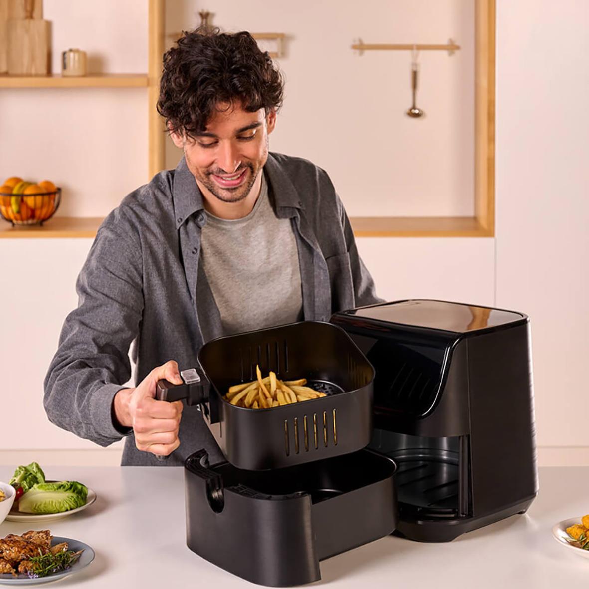 Man lagar mat i en svart luftfritös Black+Decker 1800W 5,5L i ett kök